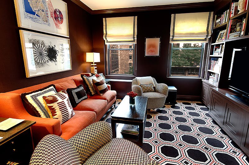 Family room with octagon graphic print rug, orange sofa, built in bookcase and diamond printed club chairs