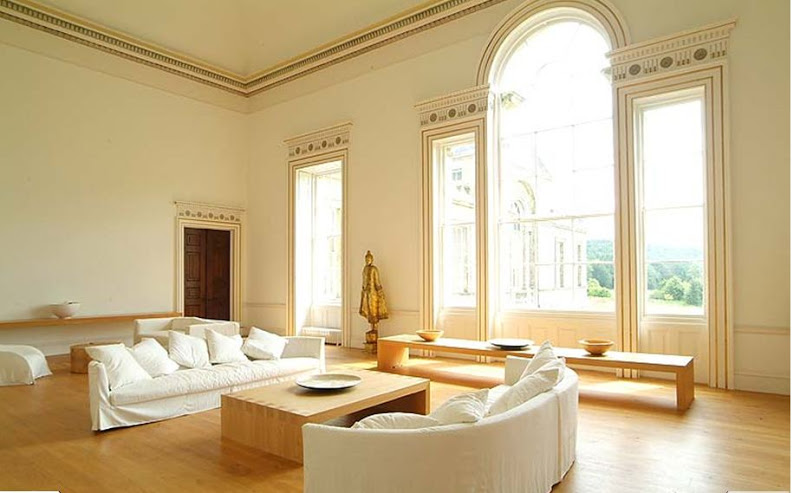 Living room in Wardour Castle with high ceiling wood floor, white sofas and armchairs and a fireplace