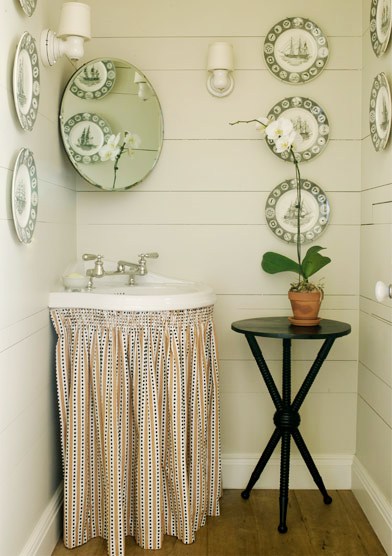 Classic country powder room with skirted sink and decorative plates