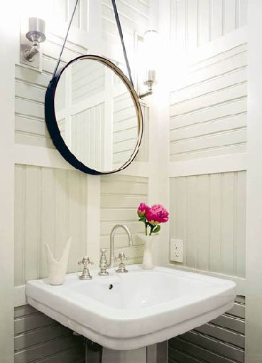 Powder room with round mirror and paneled walls