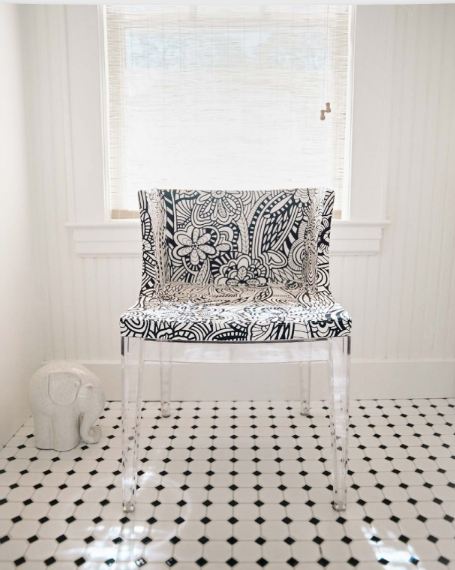 Black and white graphic printed chair with lucite legs in a bathroom with black and white tile floor