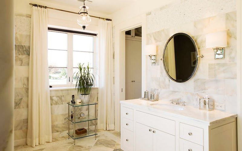 White bathroom with large marble field tiles on the wall and square floor tiles arranged in a harlequin pattern