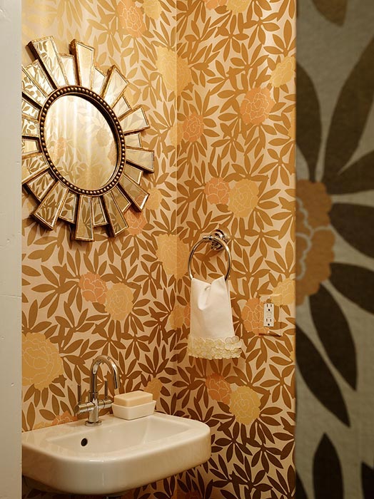 Powder room with gold and bronze floral wallpaper and a sunburst mirror