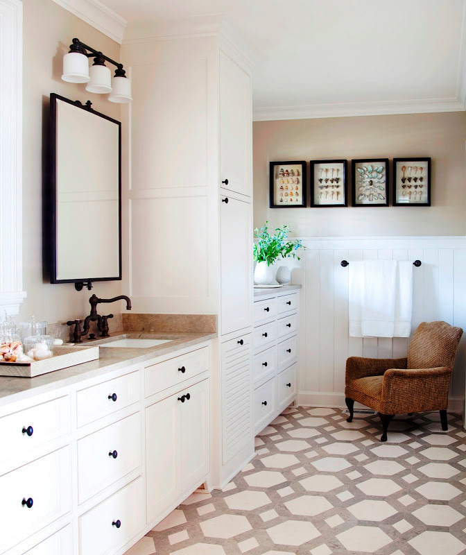 Traditional bathroom with hexagon tile floor, white drawers, beadboard walls and a brown armchair