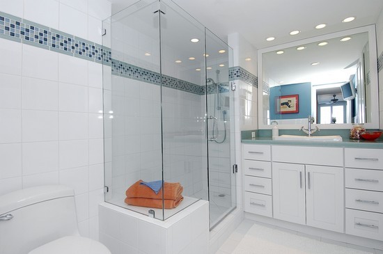 White bathroom in a beach condo with glass shower and tile border