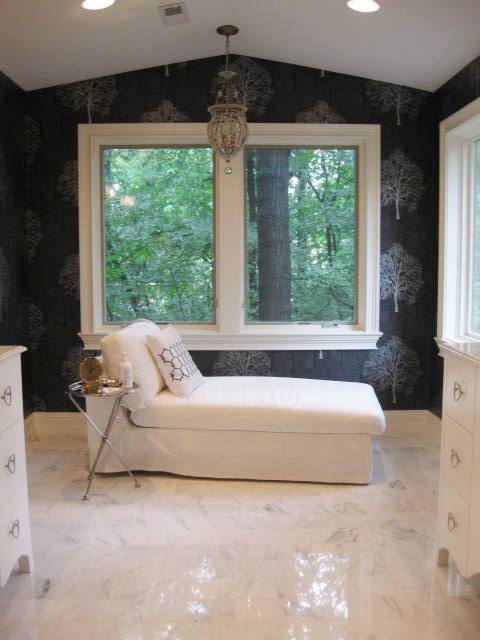 Chaise lounge in a black master bathroom with white cabinets and moldings and Carrara marble floor