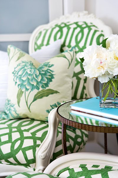 Green and white upholstered armchair with floral accent pillow in a pale bedroom