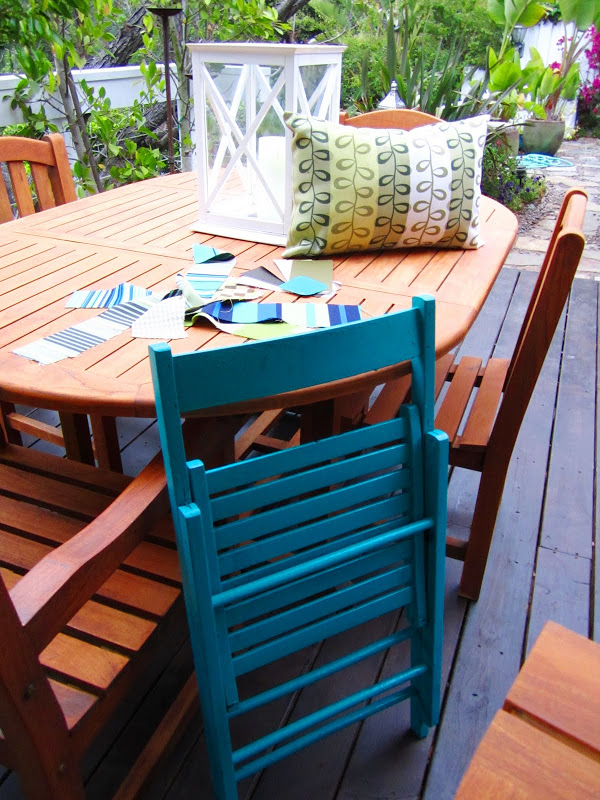 Teak outdoor dining set and a bright blue folding chair