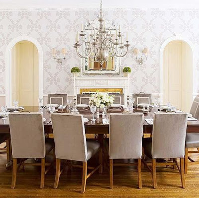 Modern-traditional dining room with grey upholstered chairs with white trim, silver chandelier, white fireplace and arched entryways 