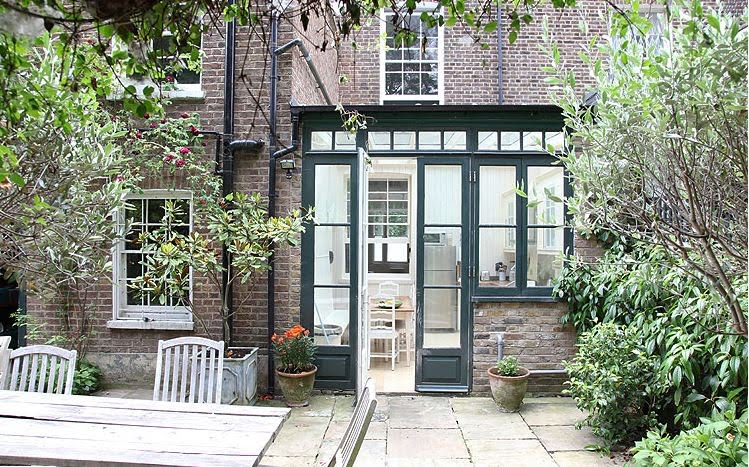Brick exterior of a London home and the outside of the glass kitchen
