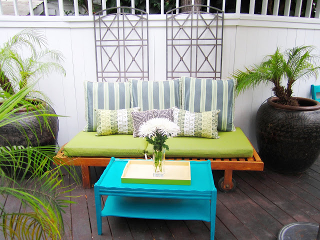 Brightly colored deck with a blue side table and playful accent pillows