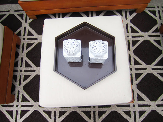 Shiny brown hexagon lacquer tray on white ottoman with two white Moroccan lanterns