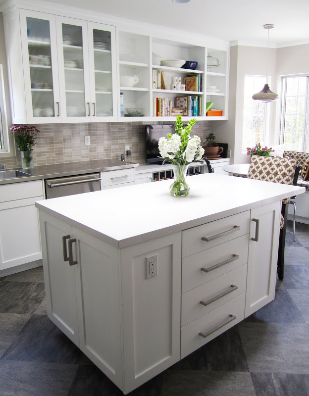 Gourmet kitchen with grey/brown backsplash, white paneled cabinets and hood and grey tiles arranged in a diamond pattern