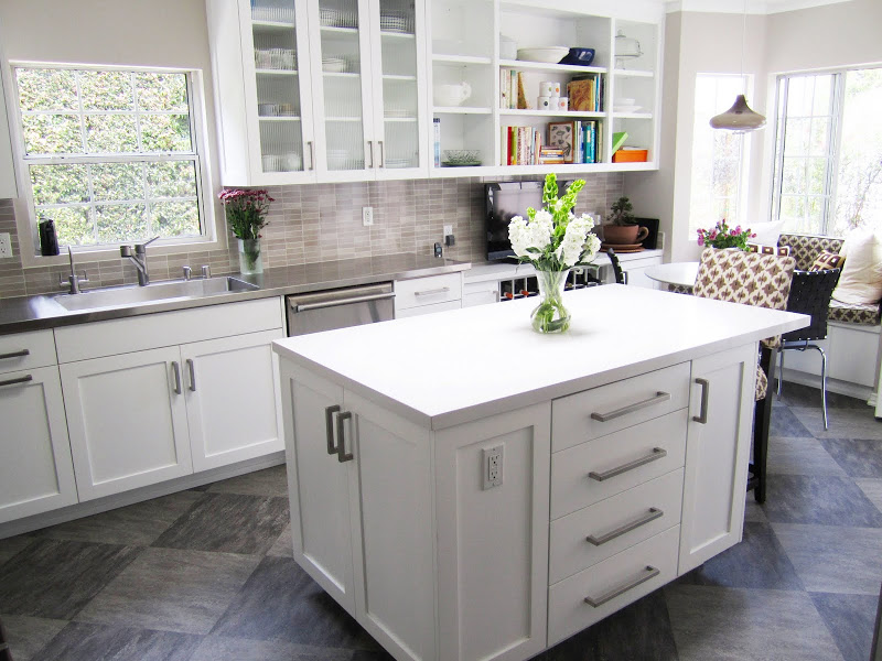 Gourmet kitchen with a breakfast nook, grey/brown backsplash, white paneled cabinets and hood and grey tiles arranged in a diamond pattern