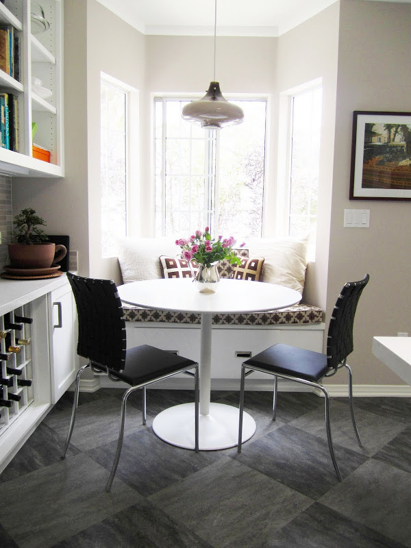 Breakfast nook with banquette seating, a pendant light and a round white table 