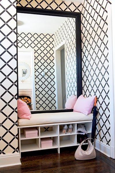 Nook with lattice print wallpaper, a bench with pink accent pillows and a large mirror