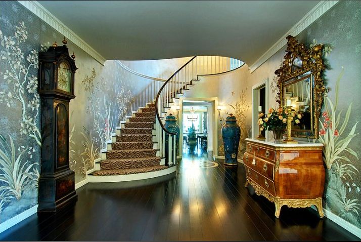 Foyer in a Paul Williams designed home with floor to ceiling wallpaper, a grand father clock, Baroque mirror and chest of drawers