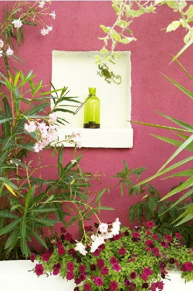 Pink outdoor wall with a white nook holding a bright green bottle 