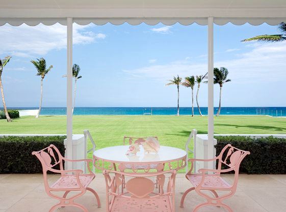 Pink outdoor table and chairs with a large green lawn and an ocean view