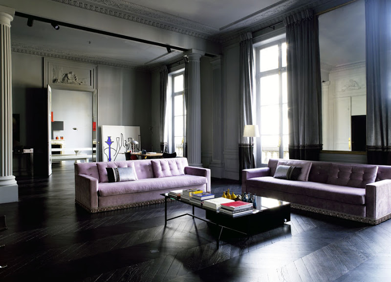 Dark grey living room with dark herringbone wood floor, purple sofas, and columns