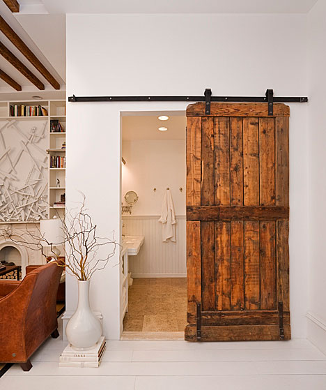 All in one kitchen, dining room, guest bedroom and small bathroom with reclaimed barn door being used as a bathroom door