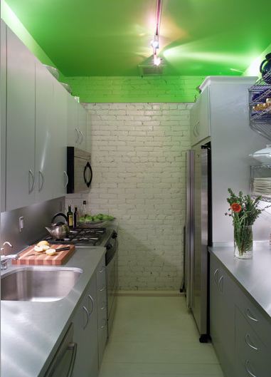 Kitchen with white washed brick wall, stainless counters and cabinets and a bright green ceiling