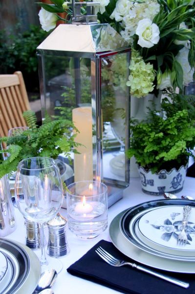 Blue and white table setting with green plants and a silver lantern