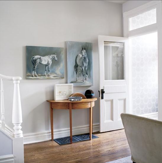Foyer in a cottage with blue-grey paintings of horses