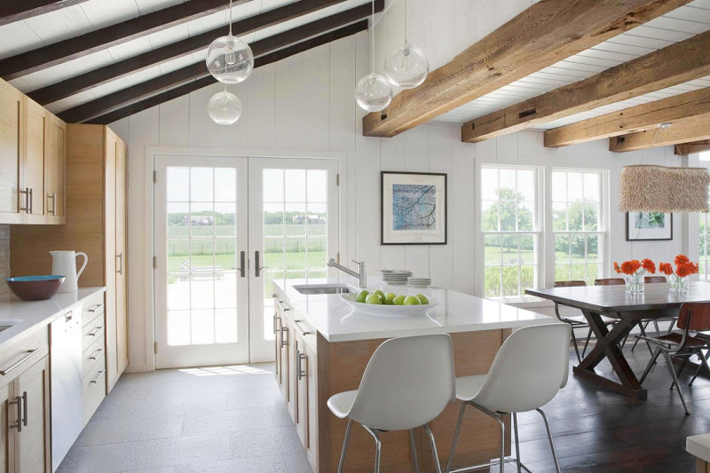 Open kitchen and dining room in the Hamptons with light wood cabinets and drawers, white countertop and four pendant lights