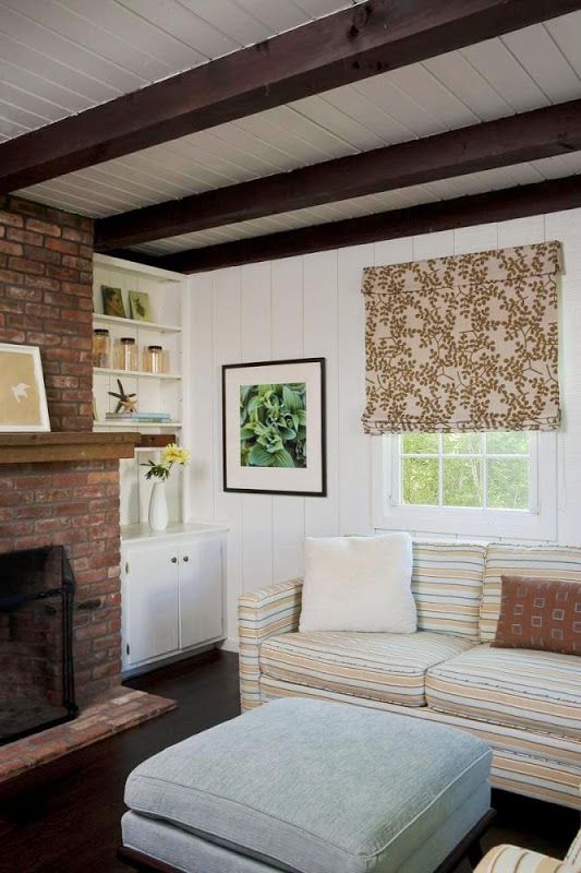 Living room in the Hamptons with striped sofa, brick fireplace and leaf print Roman shades