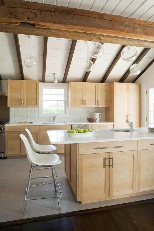 Open kitchen in the Hamptons with light wood cabinets and drawers, white countertop and four pendant lights
