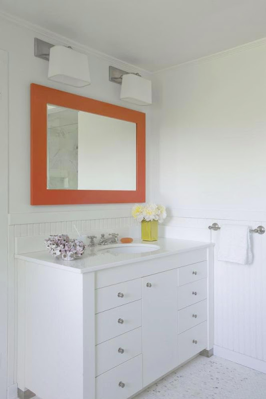 White bathroom in the Hamptons with bright orange mirror