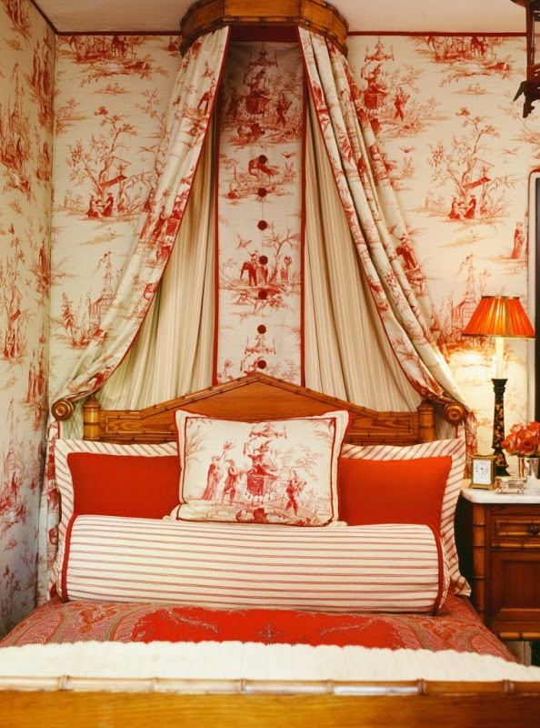 Bedroom by Martyn Lawrence Bullard with red tolie wallpaper and canopy and Moroccan inspired headboard