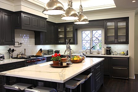 Gourmet kitchen with black cabinets and drawers, nickle pedant lights and marble countertop