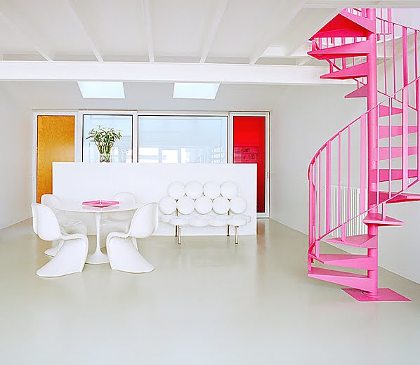 Minimalist kitchen with white Panton swoosh chairs, a Saarinen tulip table, white leather love seat and hot pink spiral staircase