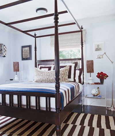 Bedroom with four poster bed and brown and cream striped rug