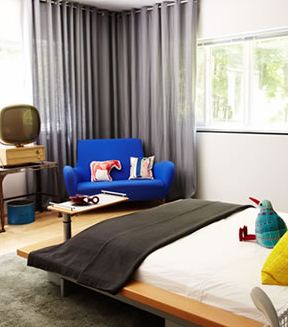 Bedroom in a modern home with a bright blue sofa and low bed