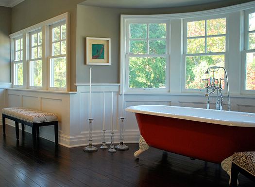 Master bathroom with wood floor, half paneled walls, red claw foot tub and bay windows