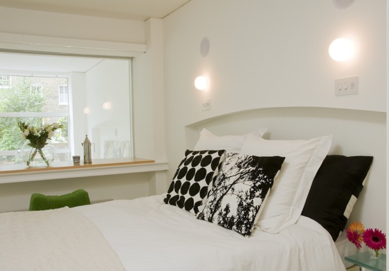 Bedroom in a London loft with a picture window, white bed with arched headboard and black and white pillows