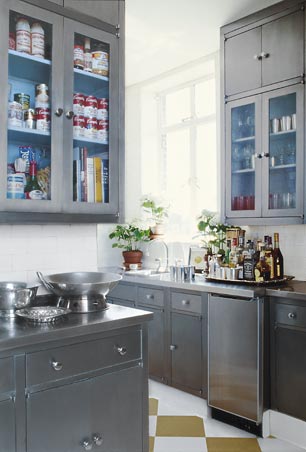 Kitchen with grey cabinets and drawers, the upper cabinets have glass doors with light blue interiors, white subway tile backsplash and gold and white checkerboard floor