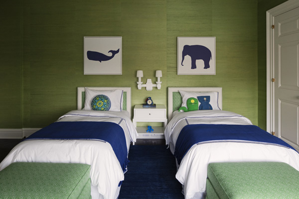Bedroom with green walls, two twin beds with white and green headboards, white bedding with blue trim, a blue throw and green ottomans at the foot of the bed