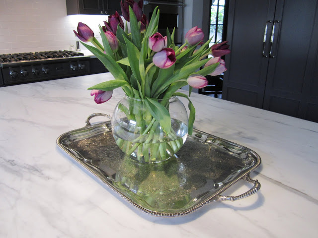 Silver Sheffield tray with a glass vase holding purple tulips on a kitchen island with marble counter top