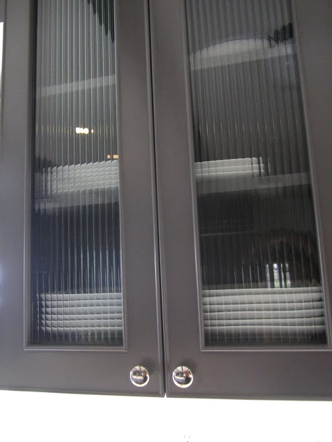 Grey cabinet with reeded glass upper cabinet doors in a kitchen