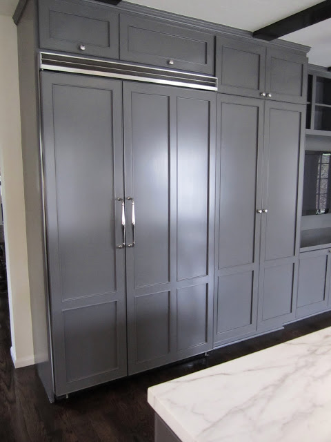 Kitchen with a double refrigerator concealed behind custom paneling