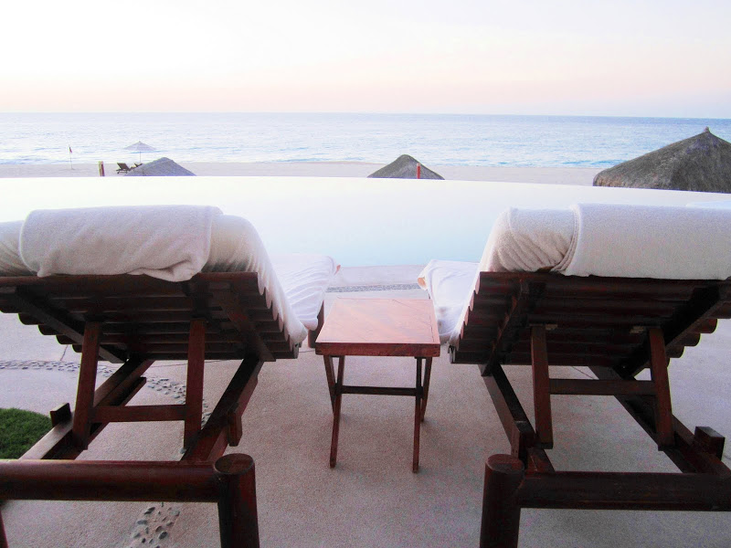 Two lounge chairs with a small table between the two at a resort in Mexico