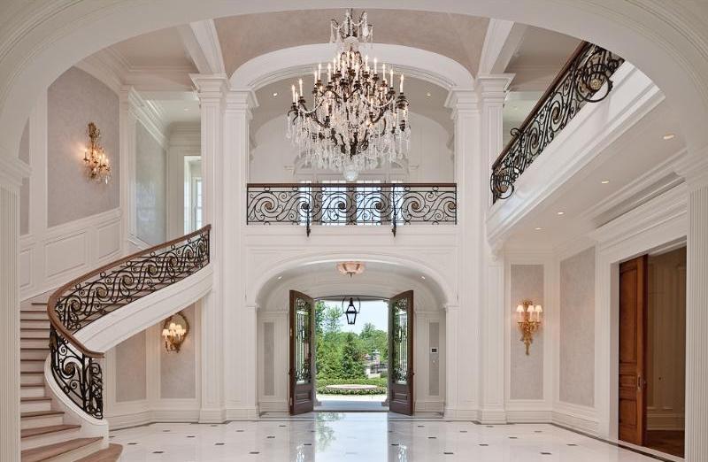 Foyer with black and white tile floor, arched ceiling, crystal chandelier, iron railings and paneled walls