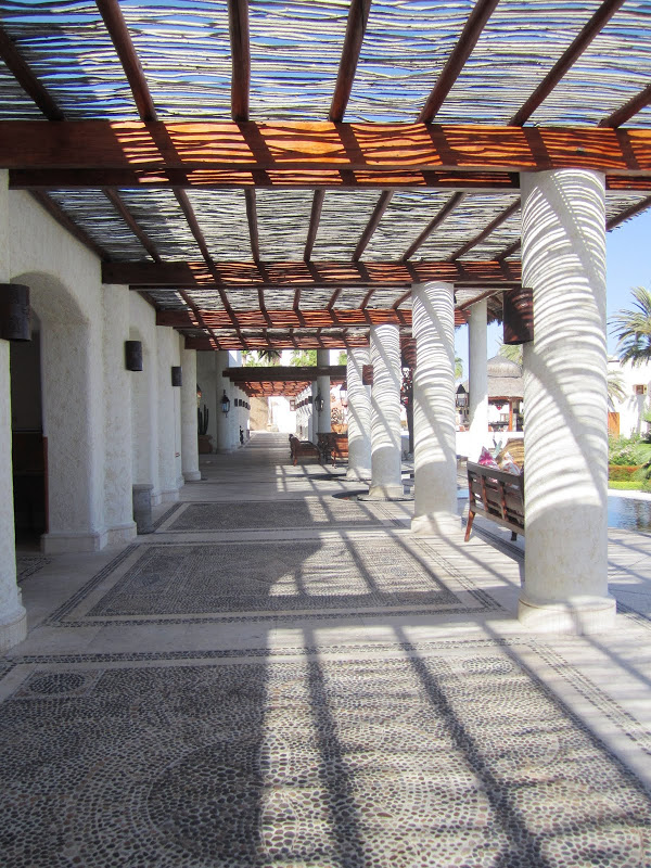 Covered walkway by a pool in Mexico with pebble mosaic floor and white columns