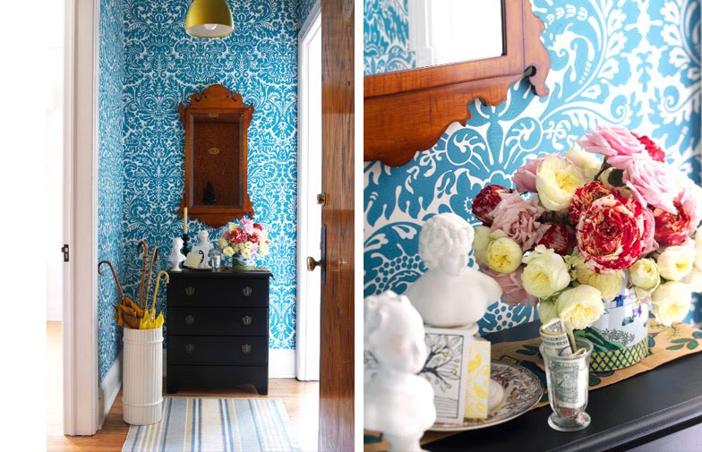 Foyer with blue and white brocade wallpaper, a black chest of drawers, a white umbrella stand and a gold pendant light