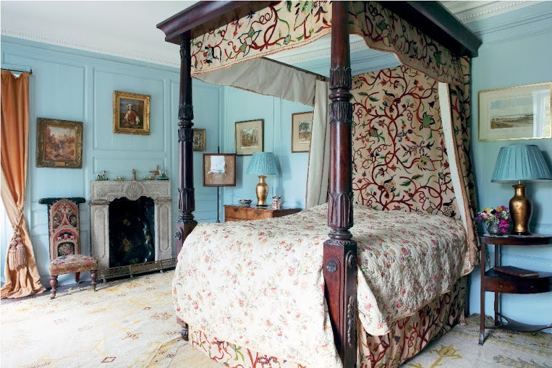 Bedroom in Glin Castle with light blue paneled walls, fireplace, antique canopy bed and orange curtains