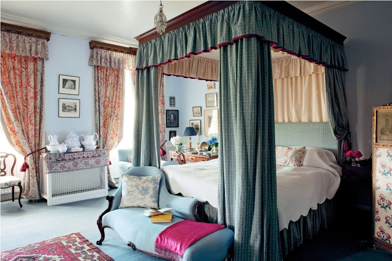 Bedroom in Glin Castle with antique canopy bed, blue chaise lounge at the foot of the bed, and large windows with brocade curtains